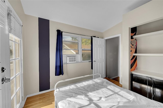 bedroom with hardwood / wood-style floors, vaulted ceiling, and a closet