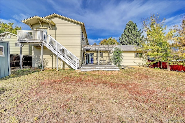 back of property with a wooden deck and a lawn