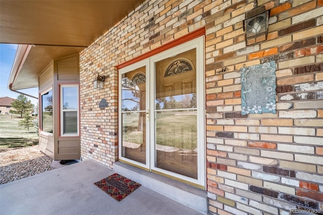 doorway to property featuring covered porch and brick siding