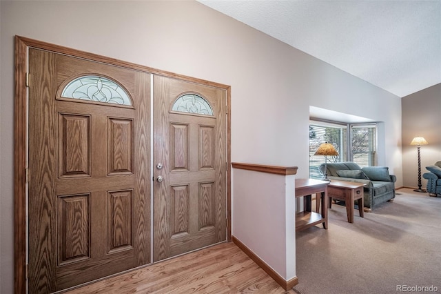 foyer entrance with baseboards and vaulted ceiling