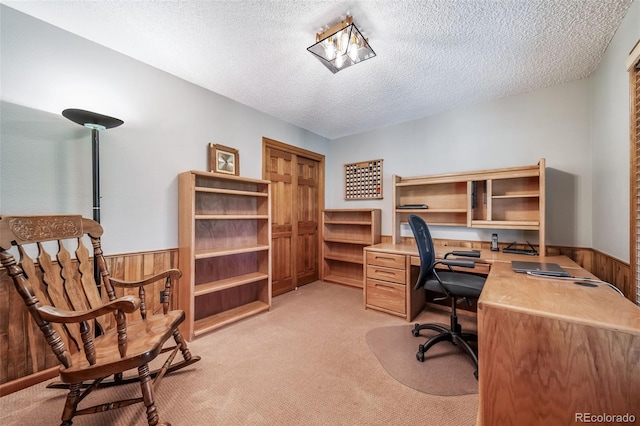office featuring light colored carpet, a textured ceiling, wainscoting, and wooden walls