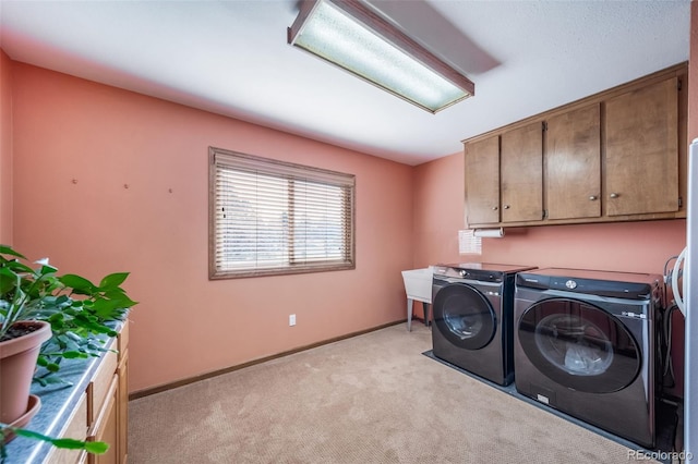 laundry room featuring independent washer and dryer, baseboards, light carpet, and cabinet space