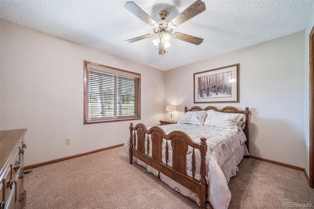 bedroom featuring baseboards, light carpet, a ceiling fan, and a textured ceiling