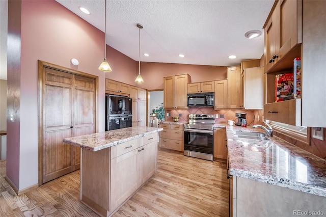 kitchen featuring a sink, a textured ceiling, light wood-style flooring, a center island, and black appliances