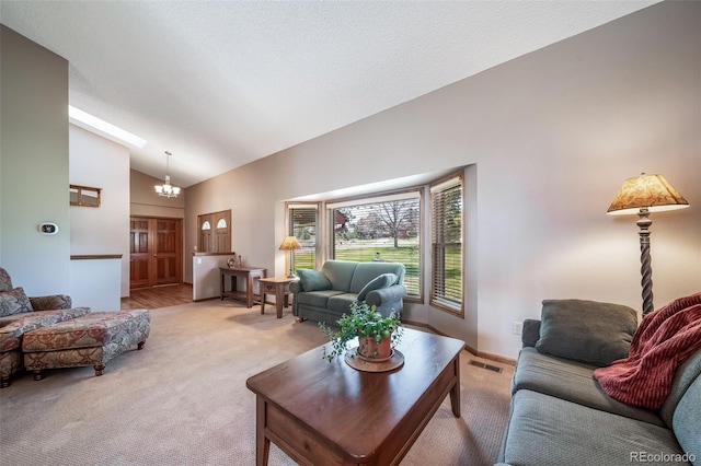 living area featuring an inviting chandelier, high vaulted ceiling, light carpet, and visible vents