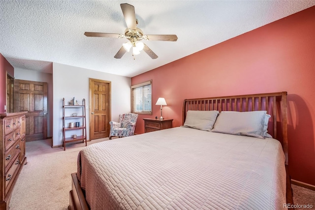 bedroom with ceiling fan, light carpet, and a textured ceiling