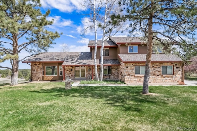 view of front facade featuring brick siding, a shingled roof, and a front yard