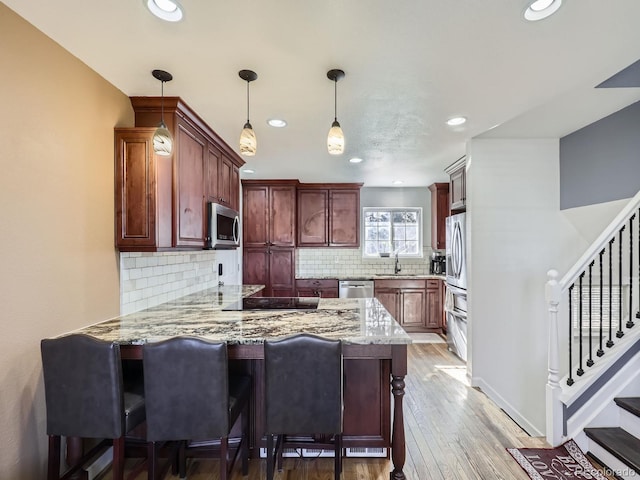 kitchen featuring sink, hanging light fixtures, a kitchen breakfast bar, kitchen peninsula, and stainless steel appliances