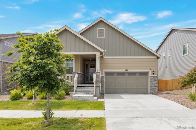 24314 E Ford Ave, Aurora, CO 80018 - view of front of house with board and batten siding, stone siding, a garage, concrete driveway, and a porch