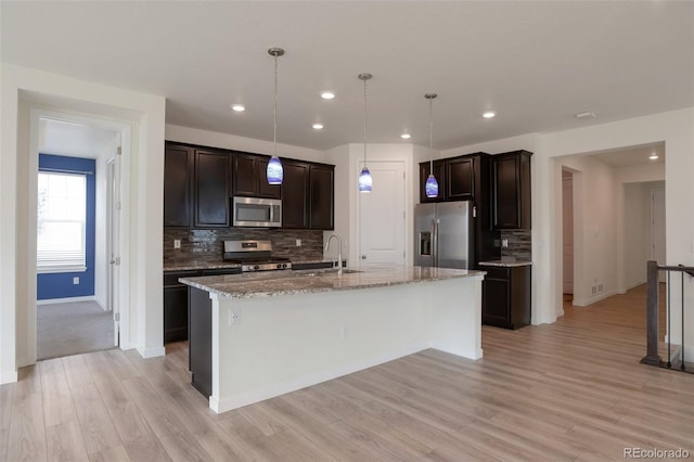 24314 E Ford Ave, Aurora, CO 80018 - kitchen with appliances with stainless steel finishes, decorative backsplash, light wood finished floors, light stone counters, and dark brown cabinetry