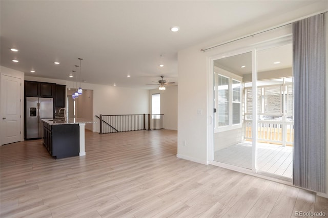 24314 E Ford Ave, Aurora, CO 80018 - kitchen featuring stainless steel fridge, open floor plan, light wood-style floors, a center island with sink, and a ceiling fan