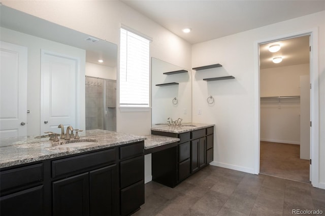 24314 E Ford Ave, Aurora, CO 80018 - bathroom featuring two vanities, tiled shower, a walk in closet, and baseboards
