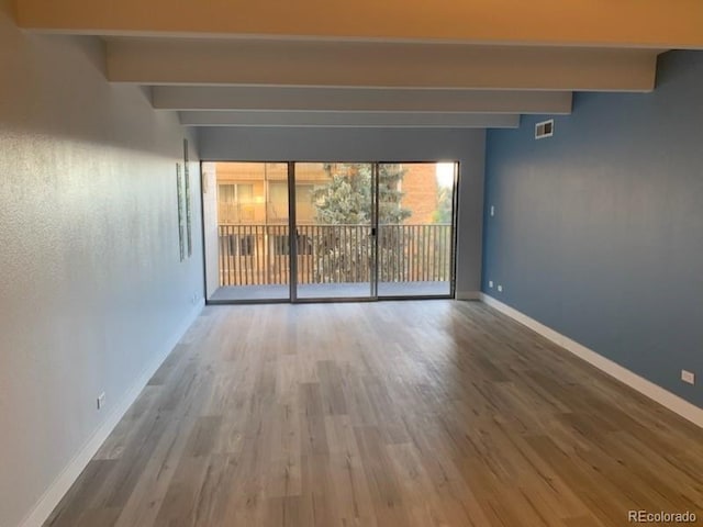 spare room with beamed ceiling and hardwood / wood-style floors