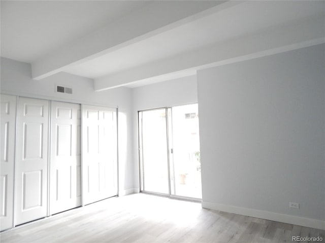 unfurnished bedroom with light hardwood / wood-style flooring and beamed ceiling