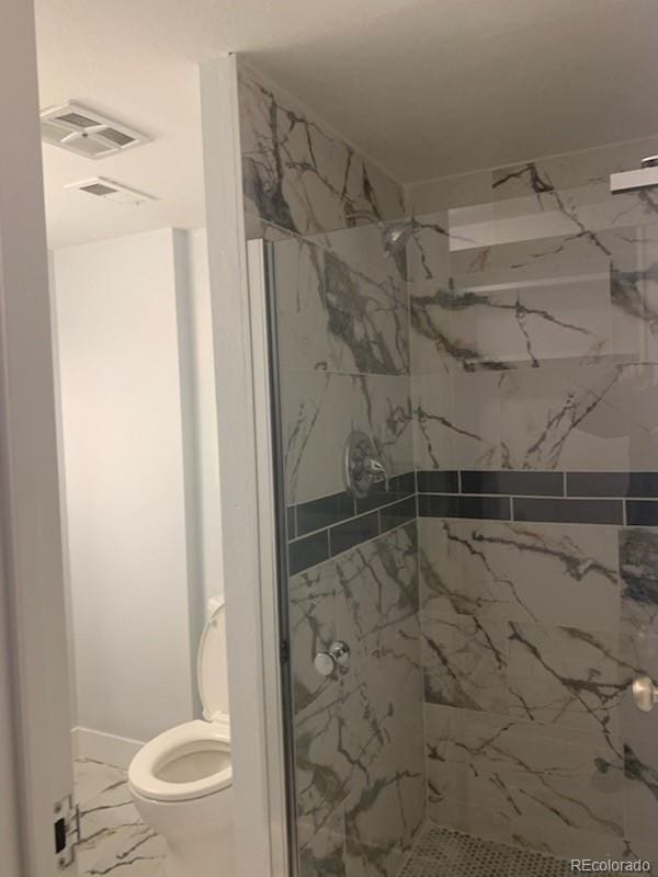 bathroom featuring a tile shower and toilet