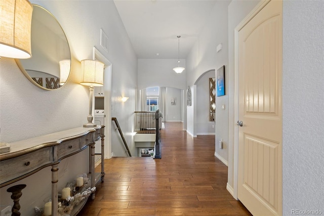 corridor with dark hardwood / wood-style floors and a towering ceiling