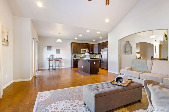 living room featuring hardwood / wood-style flooring, ceiling fan, and high vaulted ceiling