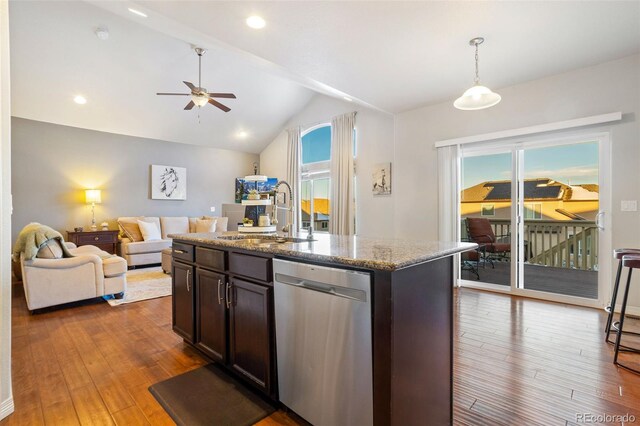 kitchen with lofted ceiling, sink, light stone counters, a center island with sink, and dishwasher