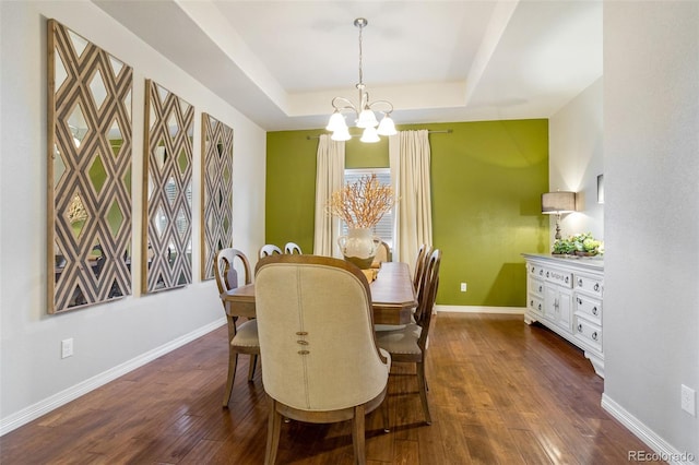 dining room with dark hardwood / wood-style flooring, a raised ceiling, and a notable chandelier