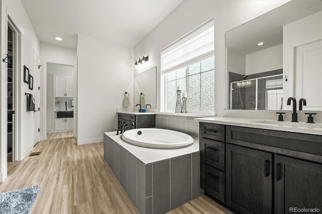 8985 Chalk Creek Pl, Littleton, CO 80125 - bathroom with two vanities, a shower stall, wood finished floors, a garden tub, and recessed lighting
