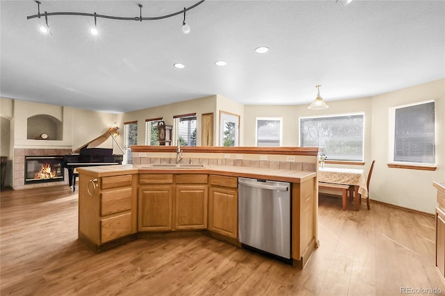 5457 S Valdai St, Aurora, CO 80015 - kitchen featuring dishwasher, tile countertops, a sink, light wood-style floors, and a fireplace
