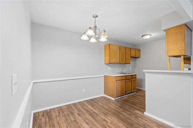 kitchen with a textured ceiling, a chandelier, wood-type flooring, and decorative light fixtures