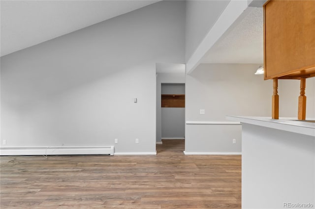 interior space with lofted ceiling, wood-type flooring, and a baseboard radiator