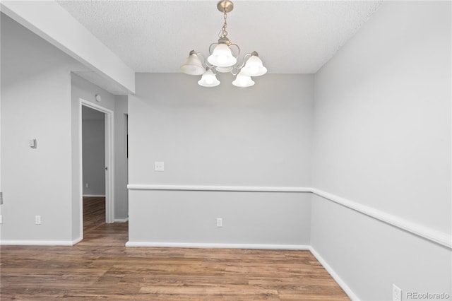 spare room with hardwood / wood-style flooring, a textured ceiling, and an inviting chandelier