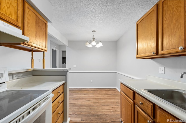 kitchen featuring sink, hanging light fixtures, a notable chandelier, light hardwood / wood-style floors, and white range oven