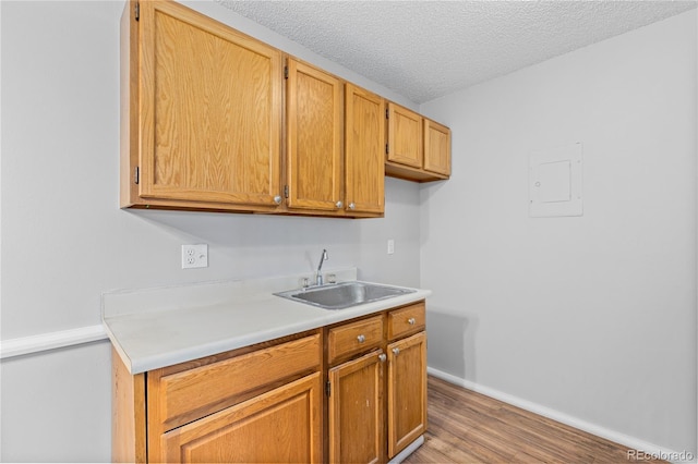 kitchen featuring a textured ceiling, light wood-type flooring, and sink