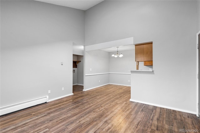 unfurnished room featuring a chandelier, dark hardwood / wood-style flooring, a towering ceiling, and a baseboard radiator