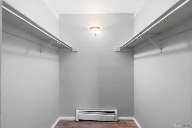 spacious closet featuring wood-type flooring and a baseboard heating unit