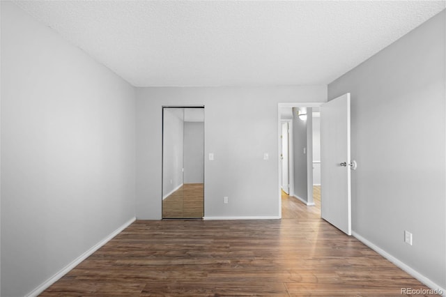 unfurnished bedroom with a closet, dark hardwood / wood-style flooring, and a textured ceiling