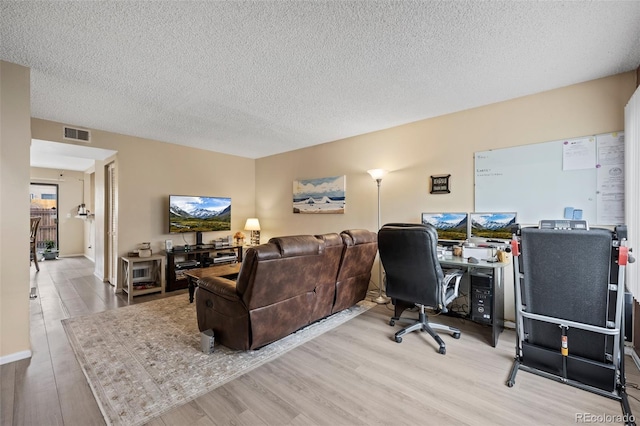 office space with light wood finished floors, visible vents, and a textured ceiling