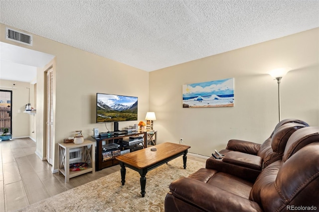 living area with baseboards, a textured ceiling, and visible vents