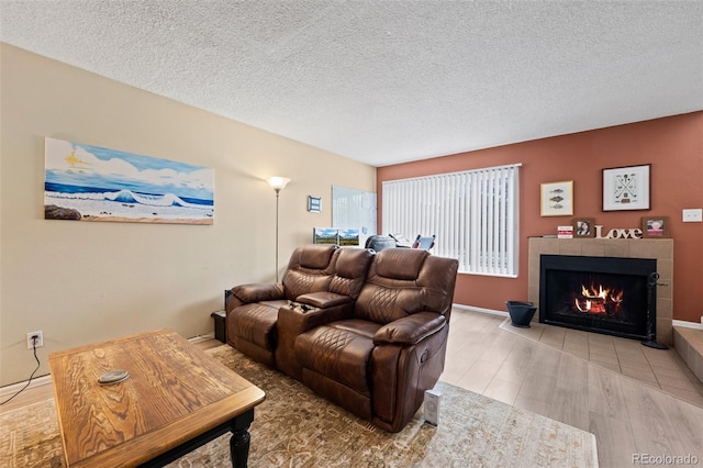 living room with a textured ceiling, wood finished floors, and a tiled fireplace