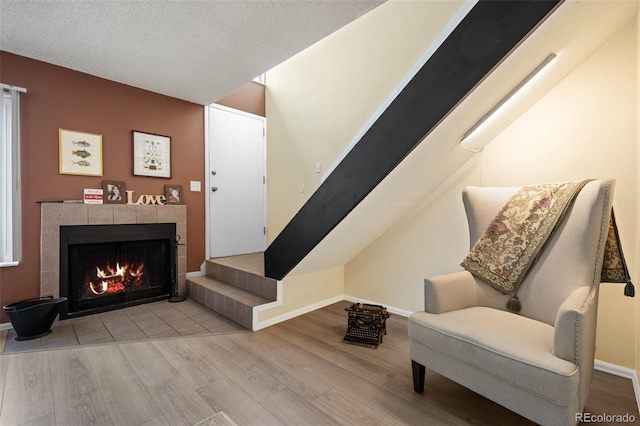 living area with a fireplace, wood finished floors, baseboards, and stairs