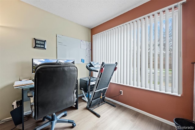 office space with baseboards, wood finished floors, a wealth of natural light, and a textured ceiling