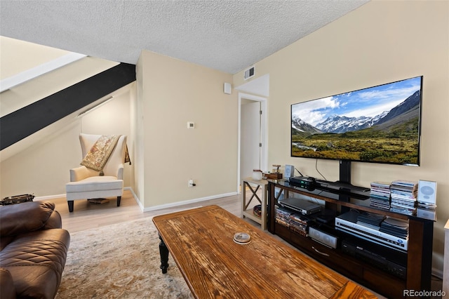 living area featuring a textured ceiling, wood finished floors, visible vents, and baseboards