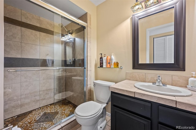 bathroom featuring a shower stall, toilet, and vanity