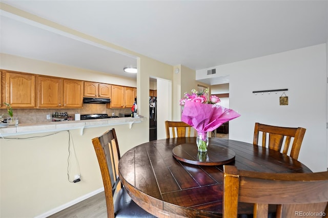 dining room with baseboards, light wood-style flooring, and visible vents