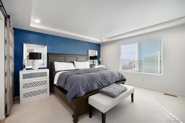 bedroom with baseboards, visible vents, a tray ceiling, light carpet, and a barn door