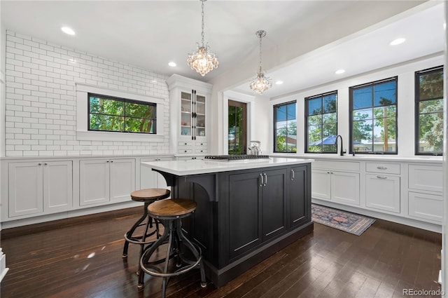 1024 Greenwood Ave, Canon City, CO 81212 - kitchen featuring a chandelier, light countertops, dark wood finished floors, white cabinetry, and a kitchen bar