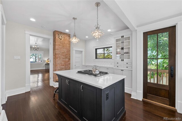 1024 Greenwood Ave, Canon City, CO 81212 - kitchen with a chandelier, stainless steel gas cooktop, dark cabinetry, light countertops, and glass insert cabinets