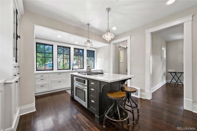 1024 Greenwood Ave, Canon City, CO 81212 - kitchen featuring stainless steel appliances, white cabinetry, light countertops, dark wood-style floors, and a kitchen bar