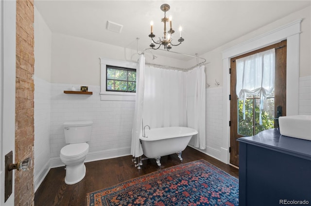 1024 Greenwood Ave, Canon City, CO 81212 - bathroom featuring wood finished floors, a soaking tub, a wainscoted wall, tile walls, and a chandelier