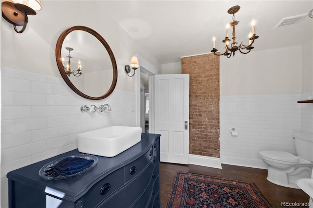 1024 Greenwood Ave, Canon City, CO 81212 - bathroom with a chandelier, tile walls, vanity, wainscoting, and wood finished floors
