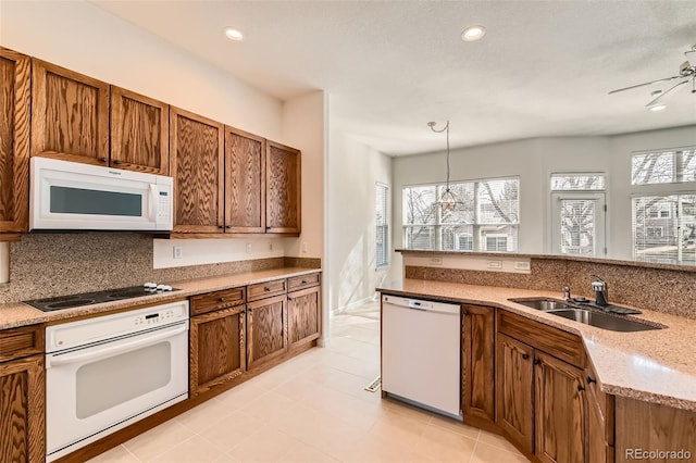 kitchen featuring white appliances, brown cabinetry, a sink, pendant lighting, and tasteful backsplash