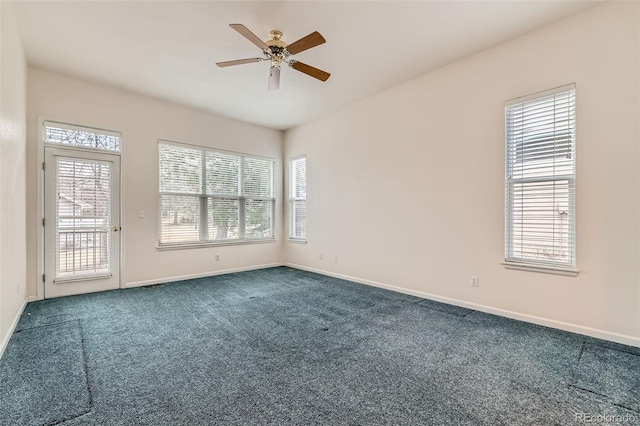 empty room with a ceiling fan, dark colored carpet, and baseboards