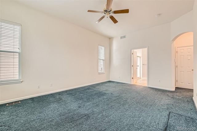 carpeted spare room with baseboards, arched walkways, visible vents, and ceiling fan